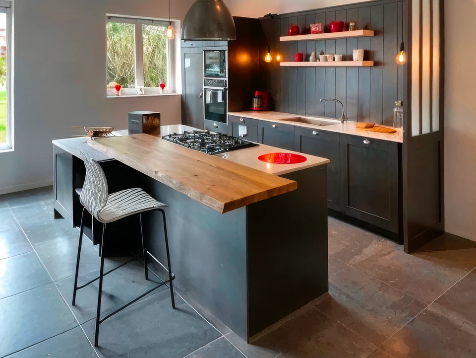 Jeune femme en tablier noir travaillant sur ordinateur portable dans cuisine professionnelle moderne, téléphone à l'oreille, prenant des notes